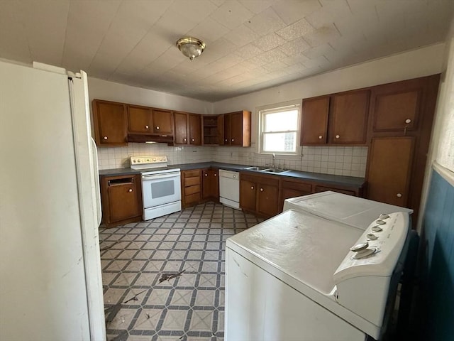 kitchen featuring under cabinet range hood, a sink, white appliances, brown cabinetry, and light floors