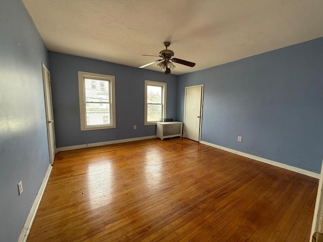 unfurnished bedroom featuring baseboards, wood-type flooring, and a ceiling fan