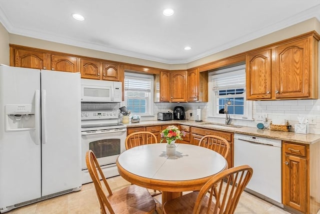 kitchen with light stone countertops, sink, backsplash, and white appliances