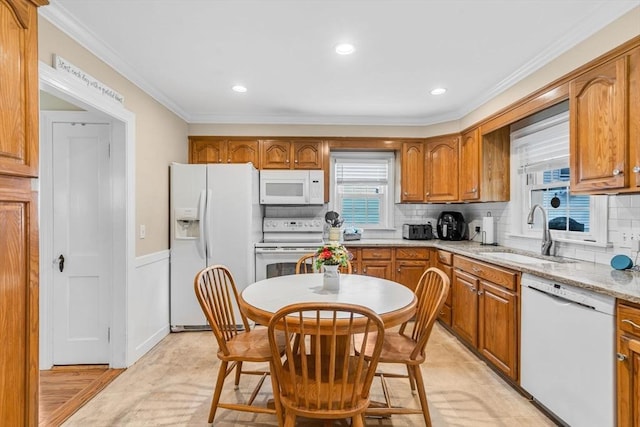 kitchen featuring sink, crown molding, white appliances, light stone countertops, and decorative backsplash