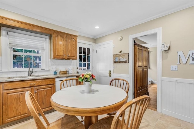 kitchen with tasteful backsplash, dishwasher, sink, ornamental molding, and light stone countertops