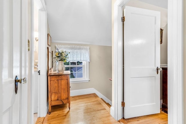 hall with light hardwood / wood-style flooring and vaulted ceiling