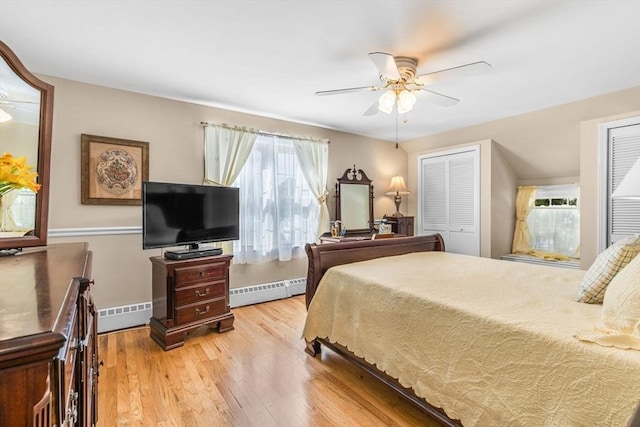 bedroom with baseboard heating, ceiling fan, multiple closets, and light wood-type flooring