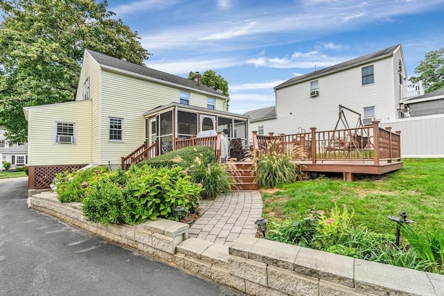 rear view of house with a sunroom and a deck