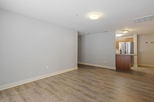 empty room with light wood-style floors, baseboards, and visible vents