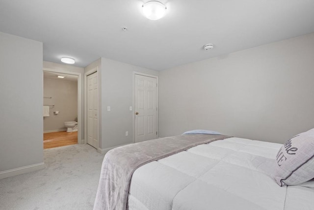 bedroom featuring baseboards, a closet, connected bathroom, and light colored carpet