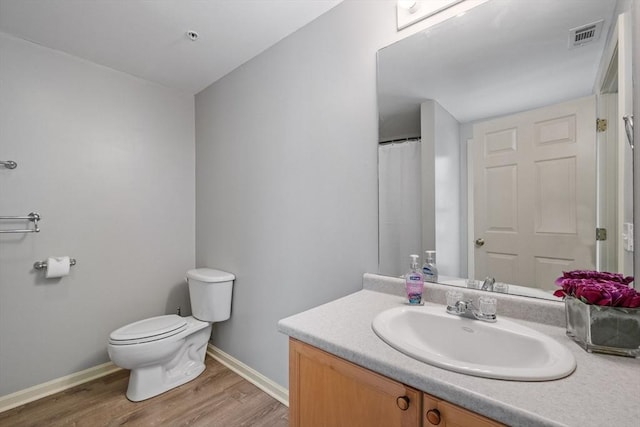 bathroom featuring visible vents, toilet, vanity, wood finished floors, and baseboards