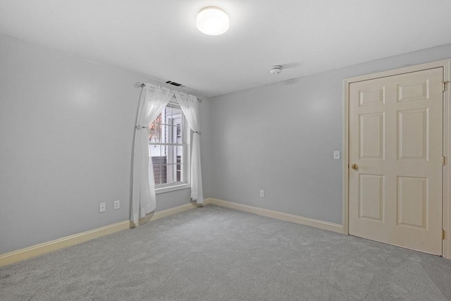 carpeted spare room with visible vents and baseboards