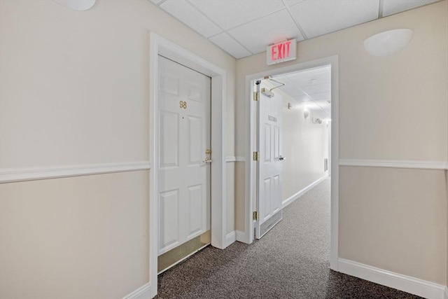 hall featuring carpet, a drop ceiling, and baseboards