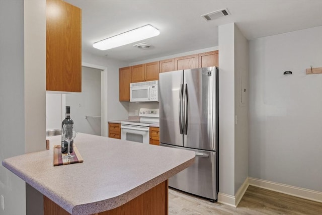 kitchen featuring white appliances, light wood finished floors, baseboards, visible vents, and light countertops