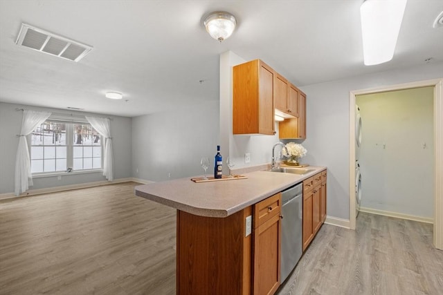 kitchen featuring a sink, visible vents, light countertops, stainless steel dishwasher, and light wood finished floors