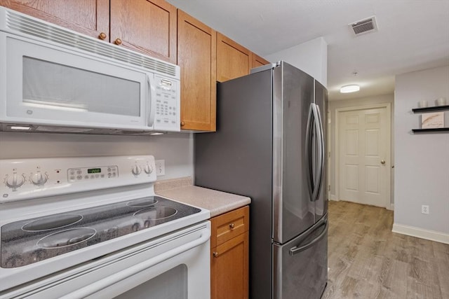 kitchen featuring brown cabinetry, white appliances, and visible vents