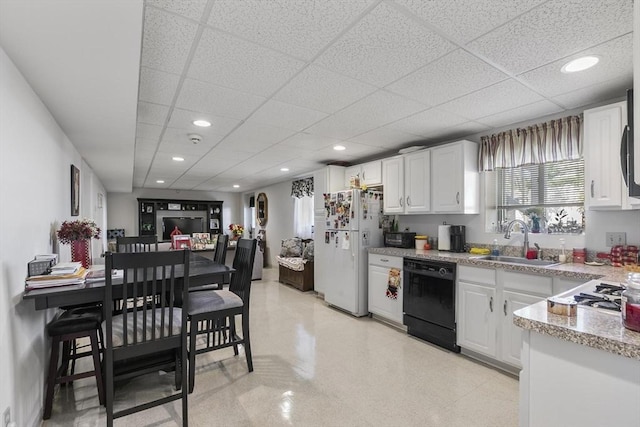 16 Windsor St, Everett, MA 02149 - kitchen featuring black dishwasher, freestanding refrigerator, a sink, white cabinetry, and a drop ceiling