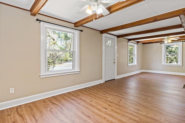 spare room featuring wood finished floors, a ceiling fan, and beam ceiling