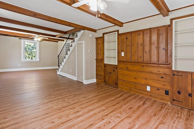 unfurnished living room with light wood-type flooring, a ceiling fan, stairs, and beamed ceiling