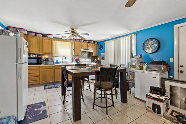 kitchen with black microwave, freestanding refrigerator, a ceiling fan, and under cabinet range hood
