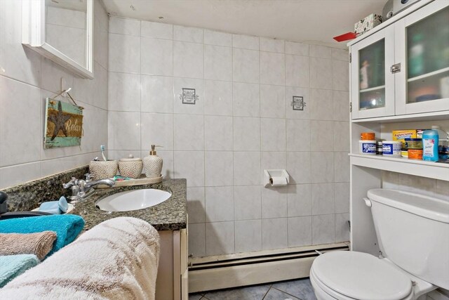 bathroom with tile walls, a baseboard heating unit, and toilet