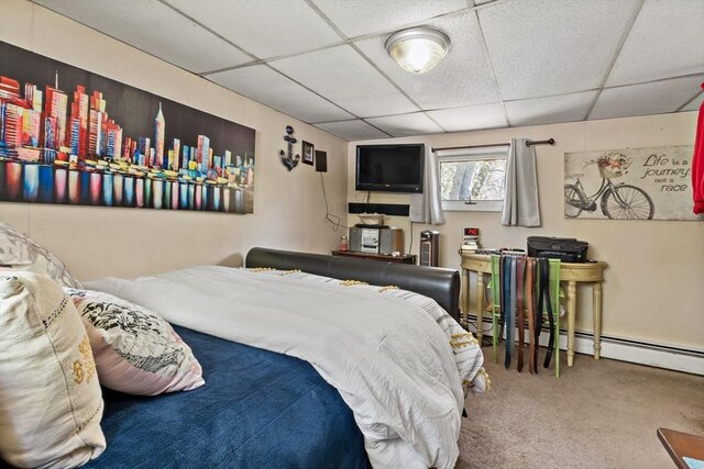 carpeted bedroom with a baseboard radiator and a drop ceiling