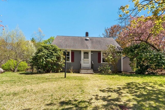 bungalow with entry steps, a chimney, and a front yard