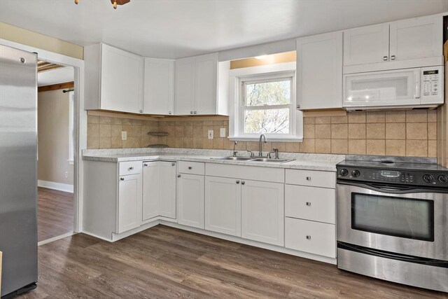 kitchen with white cabinets, a sink, light countertops, stainless steel appliances, and dark wood-style floors