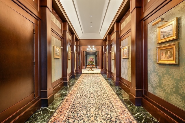 corridor featuring an inviting chandelier and crown molding