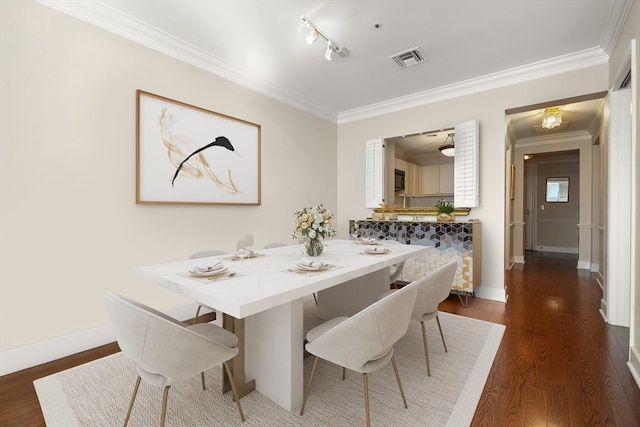 dining area featuring dark hardwood / wood-style floors, track lighting, and crown molding