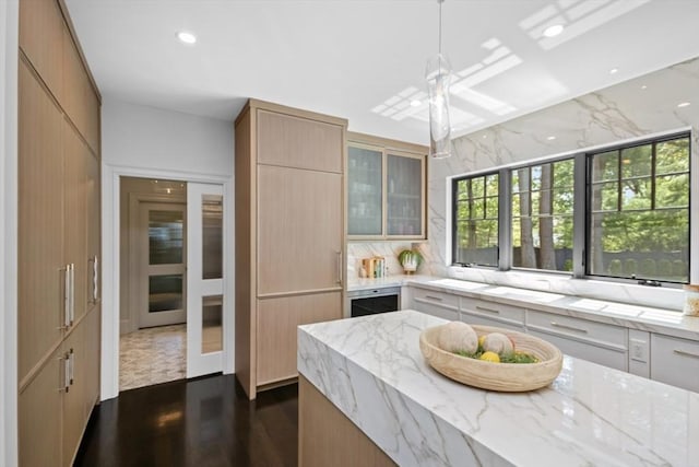kitchen featuring tasteful backsplash, light stone counters, plenty of natural light, and dark wood finished floors