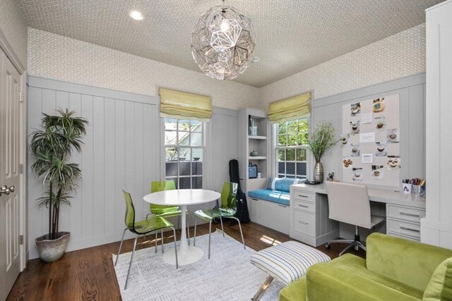 office featuring dark wood-style flooring, a decorative wall, wallpapered walls, and built in study area