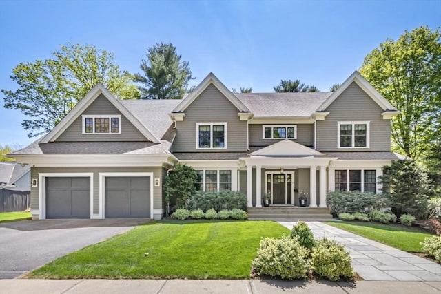 view of front facade with aphalt driveway, a shingled roof, and a front lawn