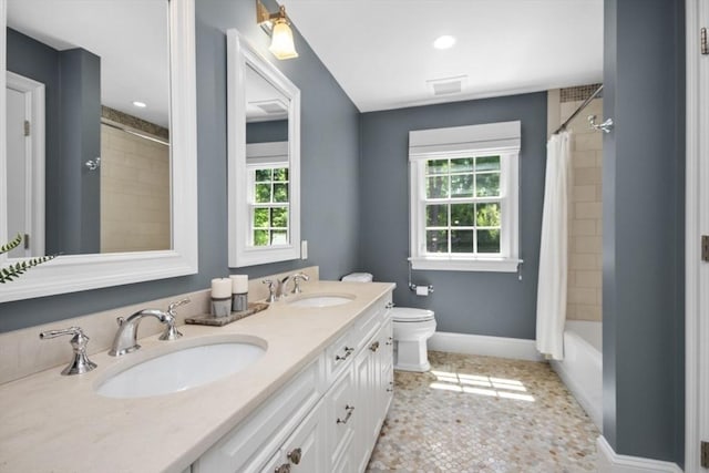 bathroom with double vanity, toilet, baseboards, and a sink