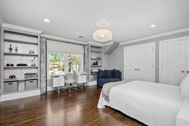 bedroom featuring crown molding, a notable chandelier, two closets, and wood finished floors