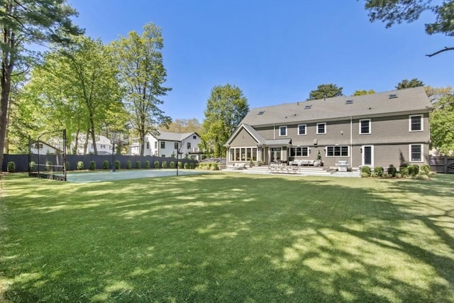 back of house featuring a trampoline, fence, a patio, and a lawn