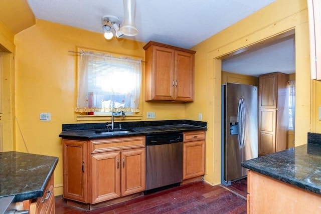 kitchen featuring sink, dark hardwood / wood-style floors, stainless steel appliances, and dark stone counters