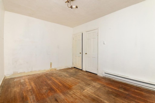 spare room featuring baseboard heating, hardwood / wood-style flooring, and a textured ceiling