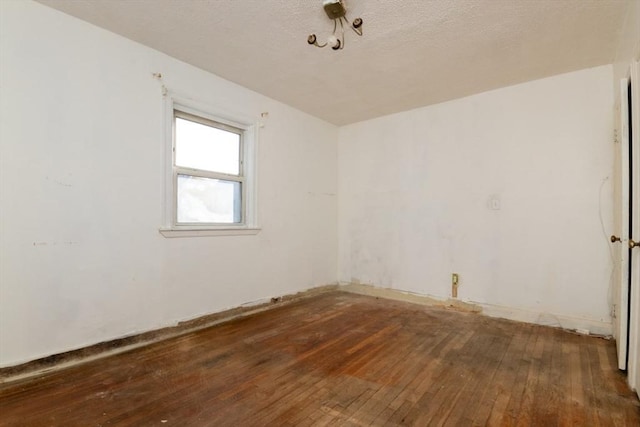 empty room with hardwood / wood-style floors and a textured ceiling