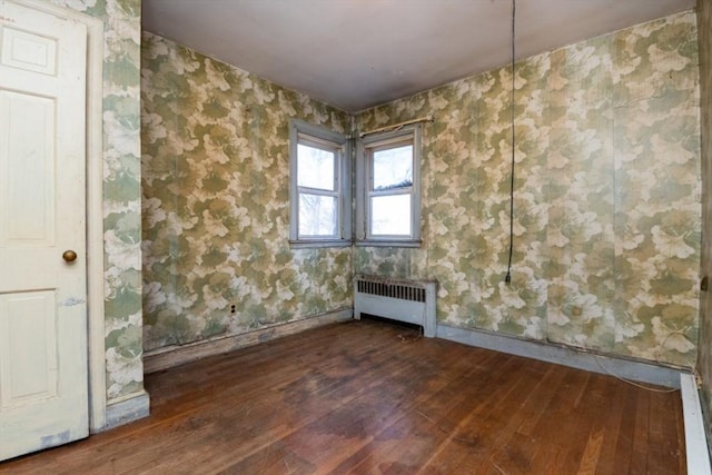 empty room with radiator and dark hardwood / wood-style flooring