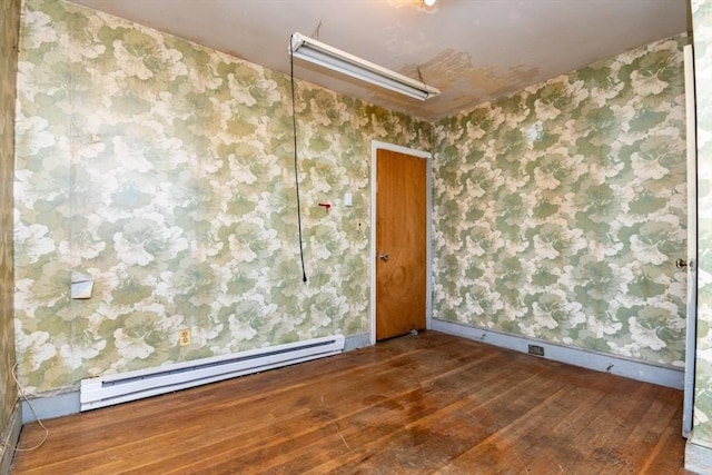 empty room featuring hardwood / wood-style flooring and baseboard heating