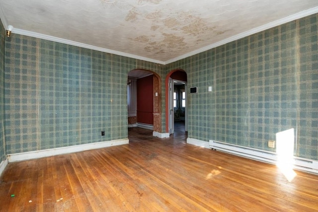 empty room featuring crown molding, hardwood / wood-style floors, and a baseboard heating unit