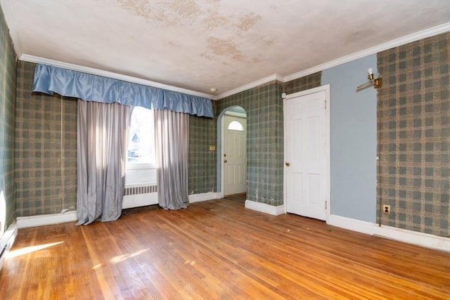 spare room featuring hardwood / wood-style floors, radiator, and ornamental molding