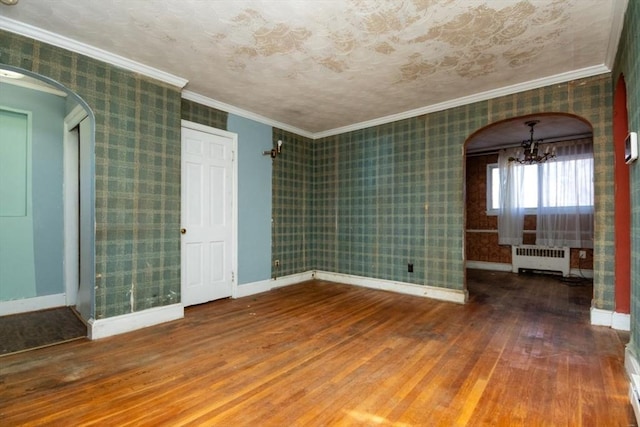 unfurnished room with wood-type flooring, radiator heating unit, a notable chandelier, and ornamental molding