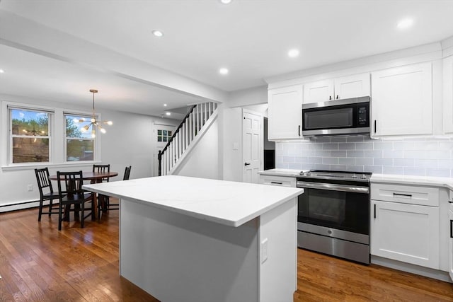 kitchen featuring stainless steel appliances, backsplash, white cabinets, a center island, and dark wood-type flooring