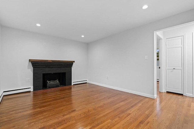 unfurnished living room with a baseboard heating unit, wood finished floors, a brick fireplace, recessed lighting, and baseboards