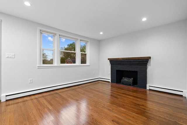unfurnished living room featuring baseboard heating, a baseboard radiator, a brick fireplace, recessed lighting, and wood finished floors
