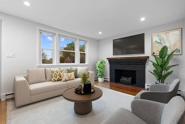 living room with wood finished floors, recessed lighting, baseboard heating, a fireplace, and baseboards