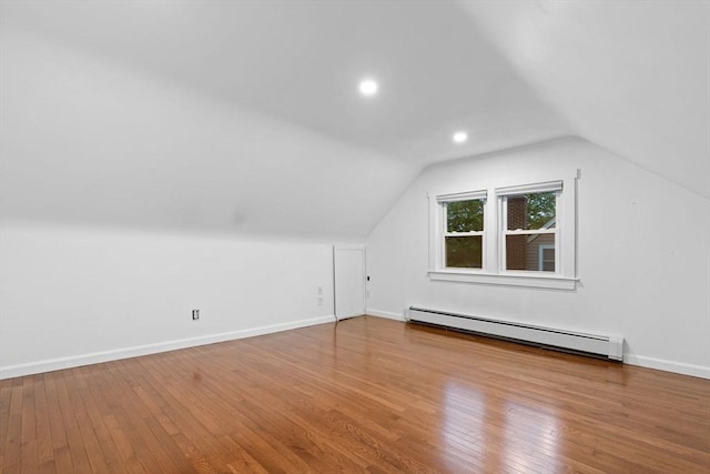 additional living space featuring baseboard heating, hardwood / wood-style floors, lofted ceiling, and baseboards