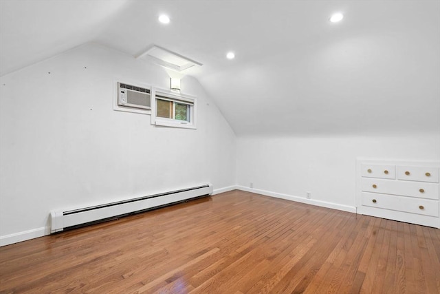bonus room featuring a baseboard radiator, an AC wall unit, vaulted ceiling, wood finished floors, and baseboards