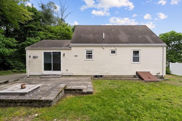rear view of house featuring a patio, an outdoor fire pit, a lawn, and roof with shingles