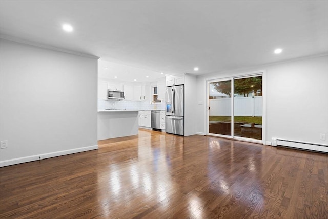 unfurnished living room with recessed lighting, wood finished floors, baseboards, baseboard heating, and crown molding
