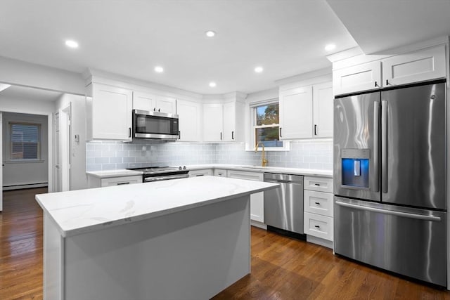 kitchen with stainless steel appliances, a sink, a baseboard heating unit, backsplash, and recessed lighting