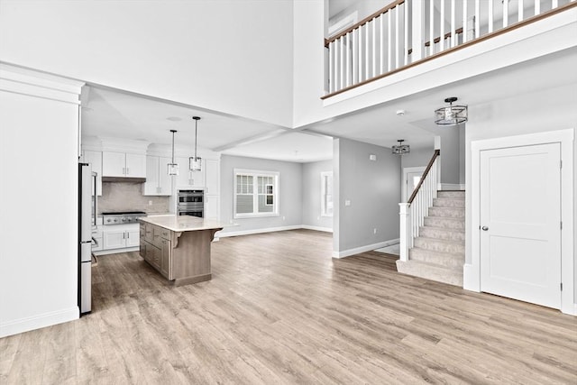 kitchen with pendant lighting, appliances with stainless steel finishes, backsplash, white cabinets, and a kitchen island